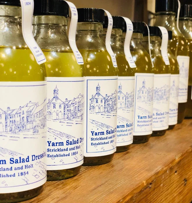 Row of bottles with Yarm Salad Dressing labels on a wooden surface