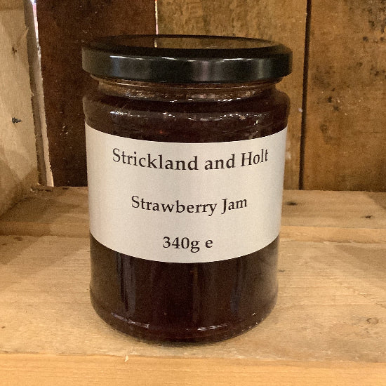 Jar of strawberry jam with a label on a wooden surface